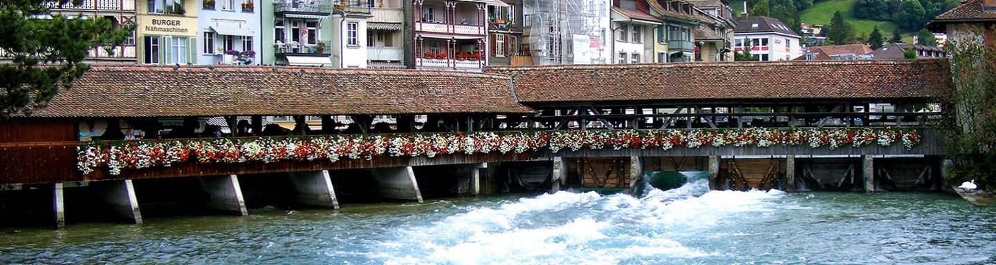 Gedeckte, kunstvoll mit Blumen geschmückte Holzbrücke über die Aare.