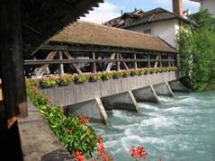 Überdachte, mit Blumen geschmückte Holzbrücke über die Aare bei Thun.