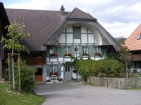 Berner Bauernhaus mit in grün-weiß gehaltenem Fachwerk und dem typischen, unten ausgehöhlten Bogengiebel (Ründe)