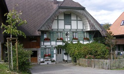 Berner Bauernhaus mit in grün-weiß gehaltenem Fachwerk und dem typischen, unten ausgehöhlten Bogengiebel (Ründe)