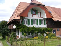 Berner Bauernhaus mit braun-weißem Fachwerk und deme typischen, unten ausgehöhlten Bogengiebel (Ründe)