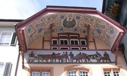 Fassade der "Alten Schaal" in Aarau mit prächtig bemaltem Bogengiebel (Ründe) und darunterliegendem Gemälde