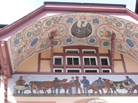 Die Fassade der "Alten Schaal" in Aarau mit prächtigem Außengemälde unter einem ebenfalls kunstvoll bemalten Bogengiebel (Ründe)